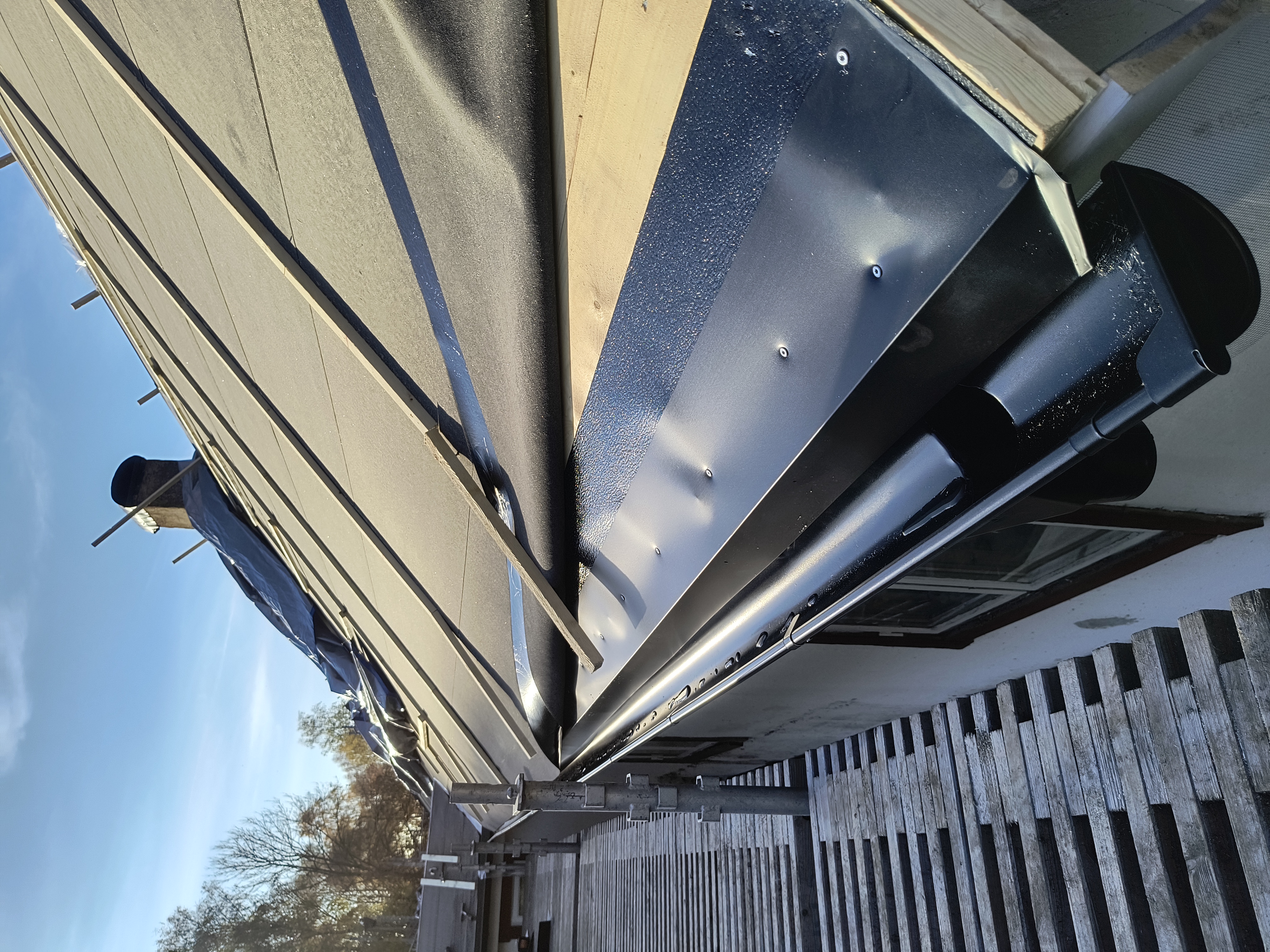 Takomläggning på en villa där nytt, tätt underlag med råspont och takpapp är lagt. Taket är nu förberett för montering av ett nytt tak.