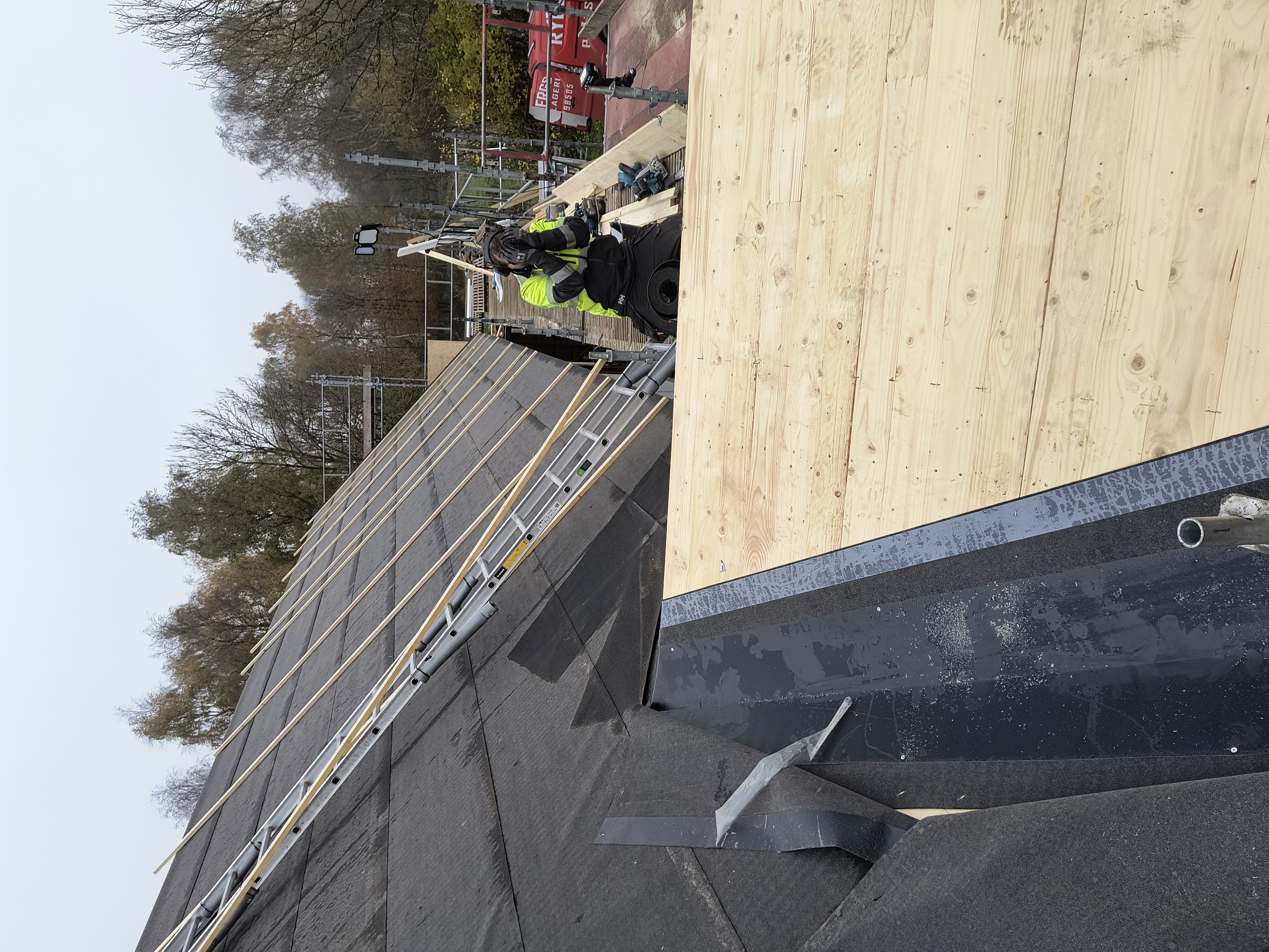 Takomläggning på en villa där nytt, tätt underlag med råspont och takpapp är lagt. Taket är nu förberett för montering av ett nytt tak.