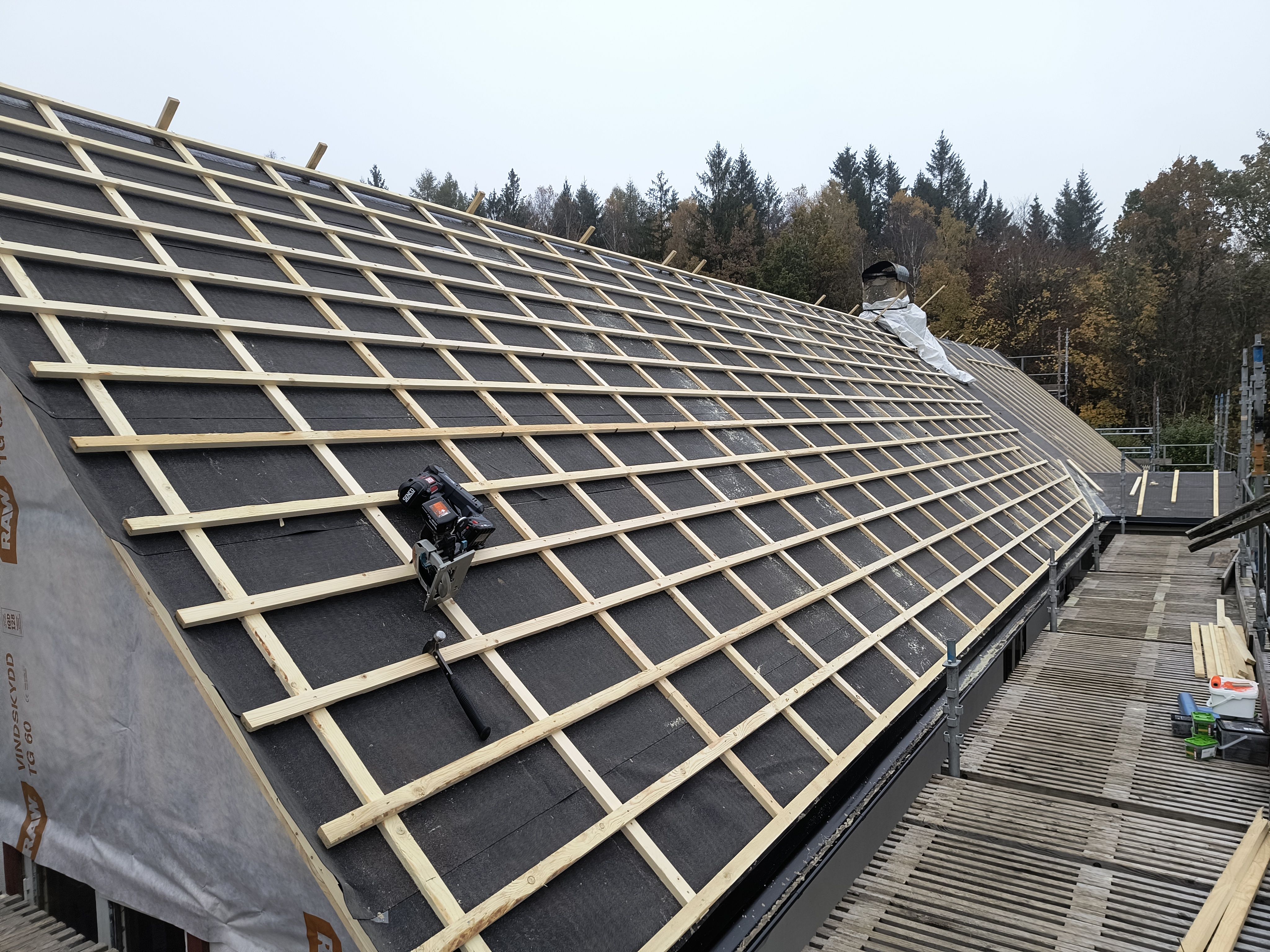 Takomläggning på en villa där nytt, tätt underlag med råspont och takpapp är lagt. Taket är nu förberett för montering av ett nytt tak.